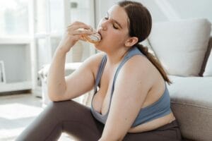 A woman in activewear relishes a donut while sitting indoors, embracing relaxation.